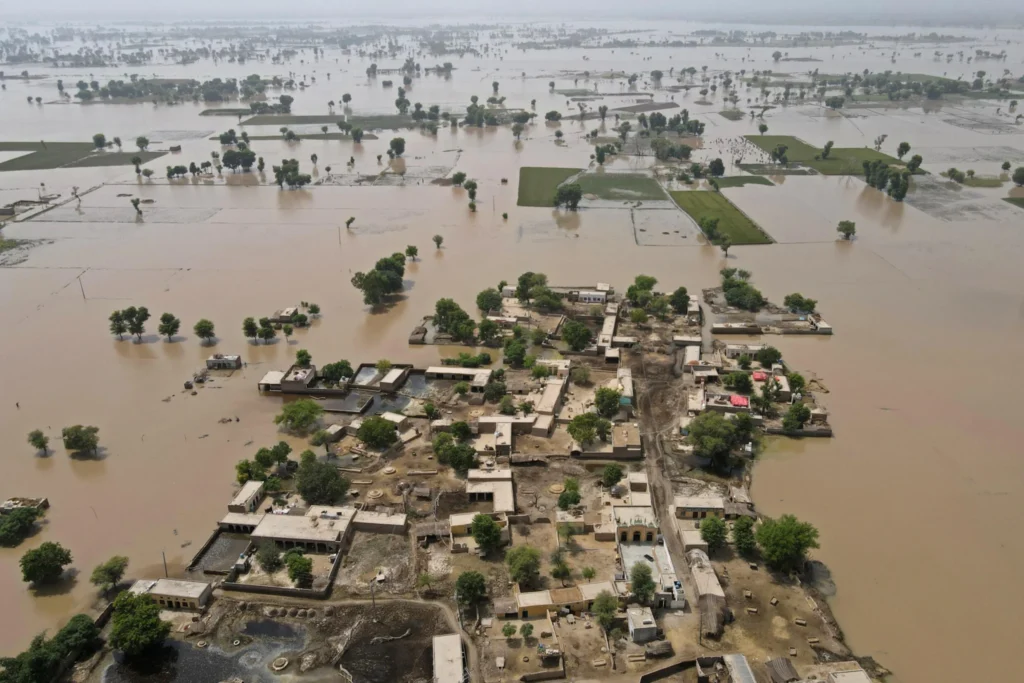 نمای هوایی از یک روستای سیلابزده و زمینهای زراعتی اطراف آن؛ خانهها تا حدی در آب فرو رفتهاند و بخشهای وسیعی از زمینهای زراعتی زیر آب قرار دارند